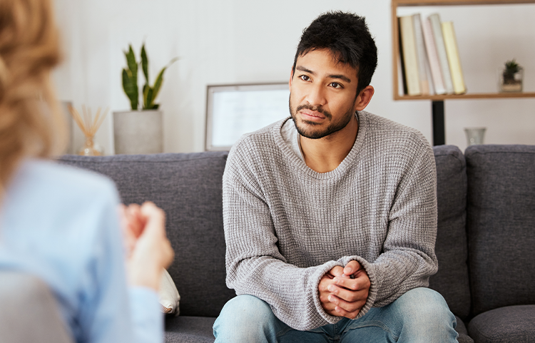 Personne assise en face d'une autre personne sur un canapé et écoutant