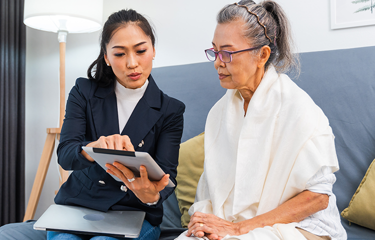 Une femme plus jeune pointe quelque chose sur une tablette pour qu’une femme plus âgée le voie.